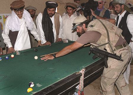 American special forces operator plays pool with men in Afghanistan