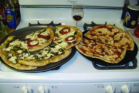 Two pizzas sitting on top of a stovetop oven